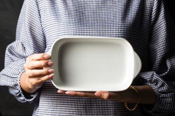 Women hold white plates in their hands.