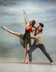 Two people dancing in contemporary stile of ballet at studio on gray