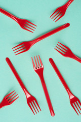 Top view of red plastic forks scattered on blue background