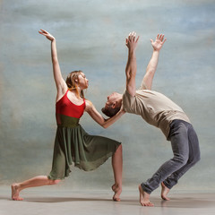 Two people dancing in contemporary stile of ballet at studio on gray