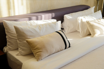 Pillows and bed sheets in luxury room with sunlight in the morning