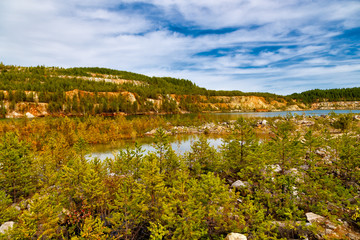 Fototapeta na wymiar flooded spruce and trees in an abandoned quarry autumn landscape with clouds