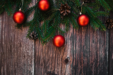 Christmas background with fir branches, red balls and pine cones on wooden. Traditional winter decor for new year with copy space. Flat lay top view