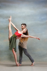 Two people dancing in contemporary stile of ballet at studio on gray