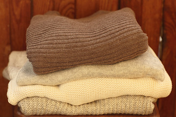 Stack of cozy woolen clothes. Knitted sweaters on the wooden table. Image toned.