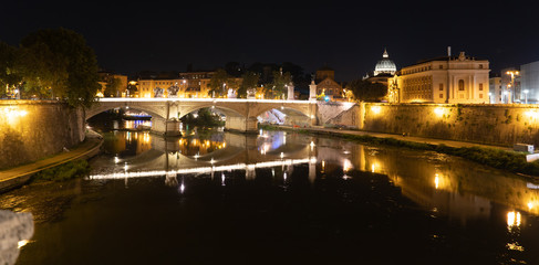 Naklejka na ściany i meble Nocturnal view of Rome, Italy: the Papal Basilica of St. Peter in the Vatican, Tiber River, Ponte Sant'Angelo bridge and Roman cityscape at night