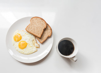 Breakfast dish of eggs and bread slice and cofee.