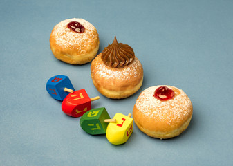 Fresh donuts and  wooden  dreidels  for Hanukkah celebration.  Hebrew letters on color dreidels say : Great Miracle Happened Here,