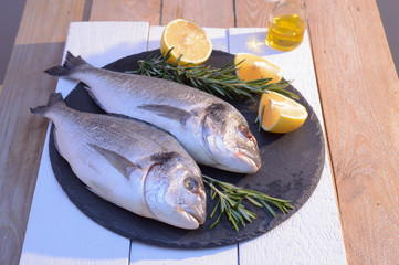 dorado fish on a black plate with lemon, rosemary