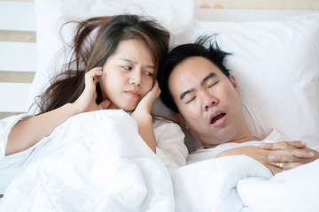 Couple on bed with white mattress Man snoring loud makes women feel annoyed. Causes Of Obstructive Sleep Apnea Stroke Chronic depression Sexual dysfunction It can be a cause of divorce in a spouse.