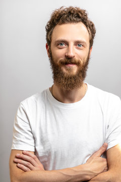 Portrait of young handsome hipster man with beard smiling at camera having positive, kind and confident look, promissing that client have made a right choice, isolated over white background.