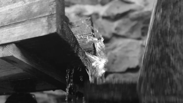 Old Wooden Water mill. Water wheel. Water falls on an old water wheel. Black and white video.