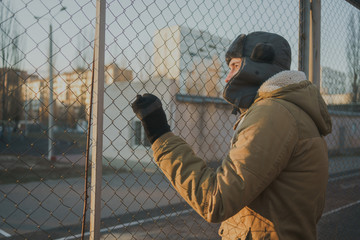 Happy handsome young man in cap with earflaps. The young man in the fur hat. a young guy standing on the street on a cloudy day. emotional portrait of a student. street style