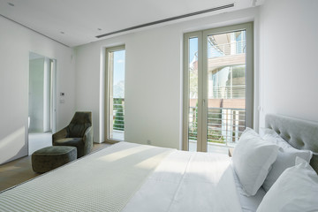 Interior of a spacious light bedroom with windows in a luxury villa