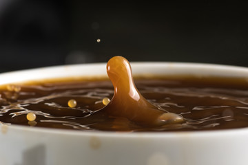 Beautiful bursts of milk drops on the surface of the coffee closeup