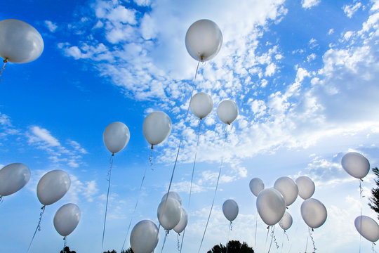 tanti palloncini bianchi che volano su nel cielo blu 