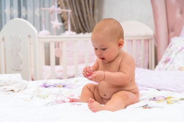 Happy chubby little baby girl playing in a cot