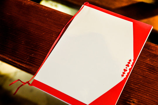 libretto messa bianco e rosso sopra banchi in legno0 di una chiesa