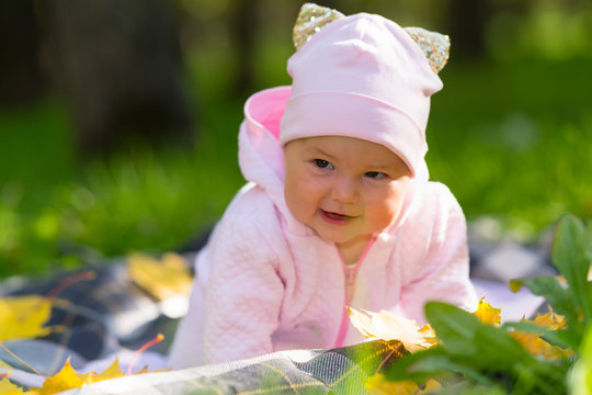 Pretty cheerful little baby girl in an autumn park
