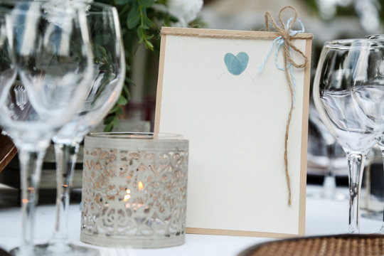 Segna posto  simpatico con cuore azzurro su tavola imbandita con calici e candele