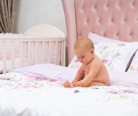 Cute little baby girl playing by herself on a bed