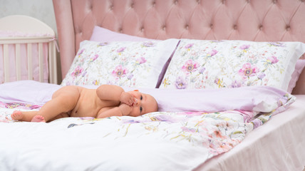 Obraz na płótnie Canvas Undressed little baby girl lying on a bed