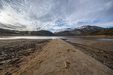 Old road in ruins that is generally flooded by the waters of the reservoir of Riaño in Leon, Spain. In the background you see the mountains between the morning mists. 