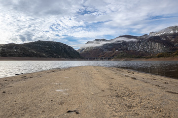 Old road in ruins that is generally flooded by the waters of the reservoir of Riaño in Leon, Spain. In the background you see the mountains between the morning mists.  - obrazy, fototapety, plakaty