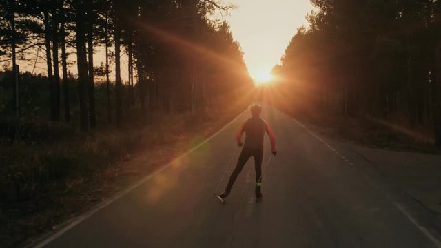 Training an athlete on the roller skaters. Biathlon ride on the roller skis with ski poles, in the helmet. Autumn workout. Roller sport. Adult man riding on skates. Shooting an athlete in motion a