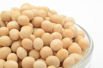 Soja amarilla cruda en un bol de cristal sobre fondo blanco