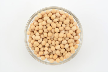 Soja amarilla en un bol de cristal sobre fondo blanco, top view