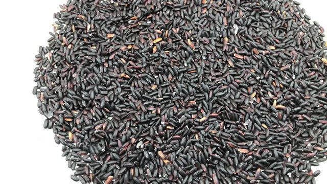 Rotating Italian Venere (Venus) rice with black grains in white background.