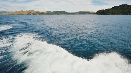 Foam wave of the sea surface from the movement of the ferry. View of the Busanga Mountains. The city of Coron. The Palawan Islands of the Philippines.
