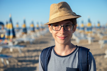 Young boy in hat and glasses posing at the summer beach. Cute smiling happy 12 years old boy at...