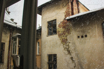 Snowing outside the window on the background of old houses