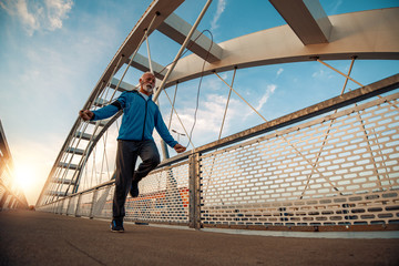 Senior man exercising with jump rope on bridge