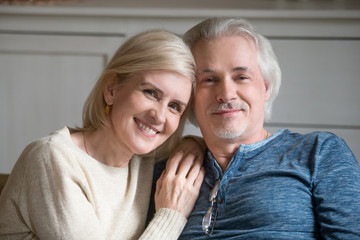 Portrait of smiling senior husband and wife hugging posing for family picture, happy aged couple embrace looking at camera enjoying weekend at home together. Elderly love, relationships goal concept