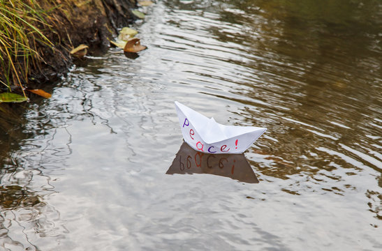lonely white paper boat called peace floating on a stream