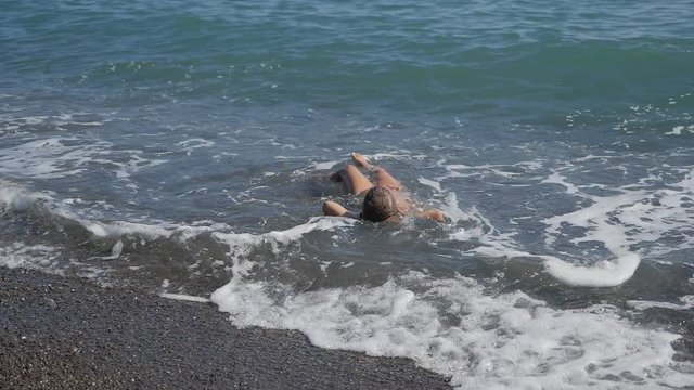 baby on the beach, in the maritime wave. boy on the golden sand plays in the surf.