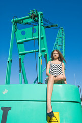 Young beautiful woman sits on big construction crane cabin