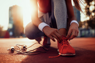 Woman tying sports shoe - Powered by Adobe