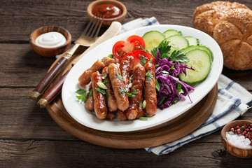 Tasty grilled sausages with vegetable salad in white plate