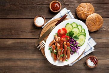 Tasty grilled sausages with vegetable salad in white plate