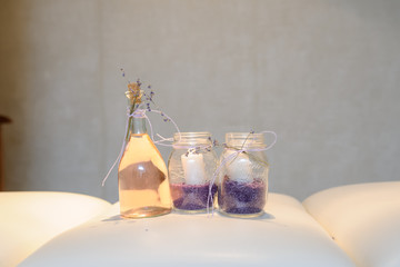lateral view of a vintage bottle with massage oil and 2 glasesses with candles and lavanda bath salt on a massage bed
