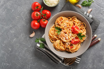 Pasta, spaghetti with tomato sauce in gray bowl on grey background. Copy space.