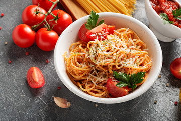 Pasta, spaghetti with tomato sauce in white bowl on grey background. Copy space.