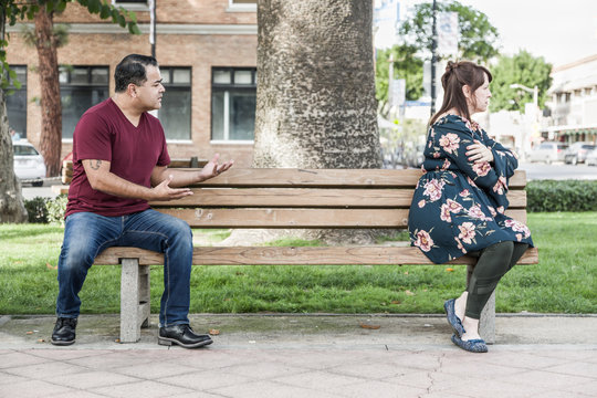 Unhappy Mixed Race Couple Sitting Facing Away From Each Other On Park Bench