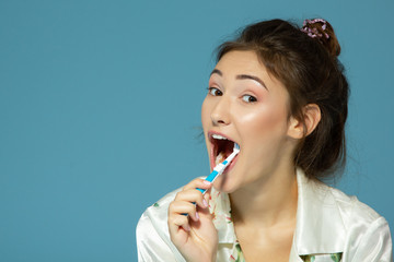 Happy funny teen girl brush her teeth, healthy concept. Morning theme, over blue background.