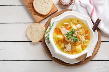Chicken soup with noodles and vegetables in white bowl on white  wooden background