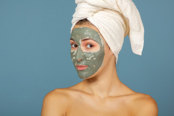 Beautiful cheerful teen girl applying facial clay mask. Beauty treatments, isolated over white background.